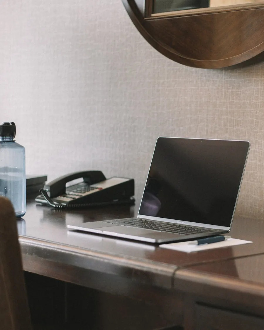 Laptop on a hotel desk next to a desk phone